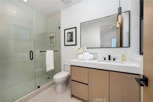 bathroom featuring toilet, vanity, tile patterned flooring, and a shower with door