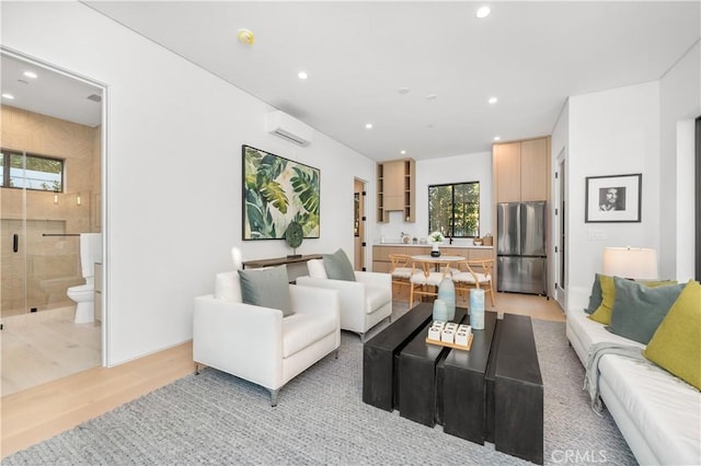 living room with a wall mounted AC and light hardwood / wood-style flooring