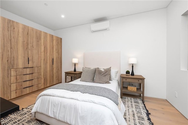 bedroom featuring light wood-type flooring and a wall mounted air conditioner