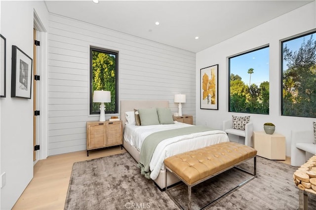 bedroom with light hardwood / wood-style flooring and wooden walls