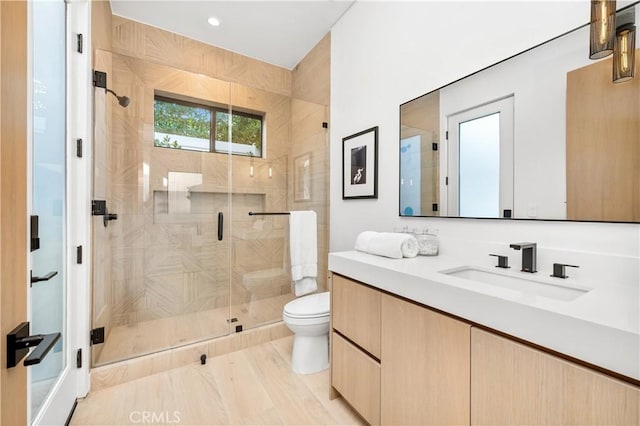 bathroom featuring toilet, a shower with shower door, and vanity