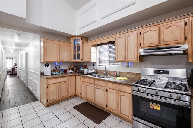 kitchen featuring light tile patterned floors, gas range, light brown cabinets, and sink