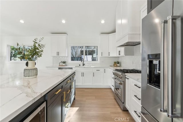 kitchen with light stone counters, sink, white cabinets, and high quality appliances