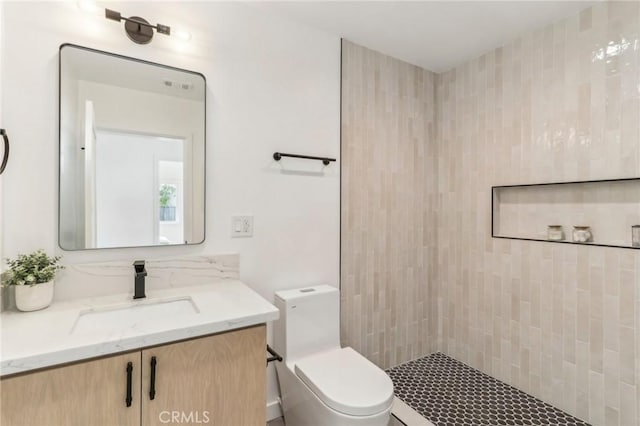 bathroom with vanity, toilet, and a tile shower