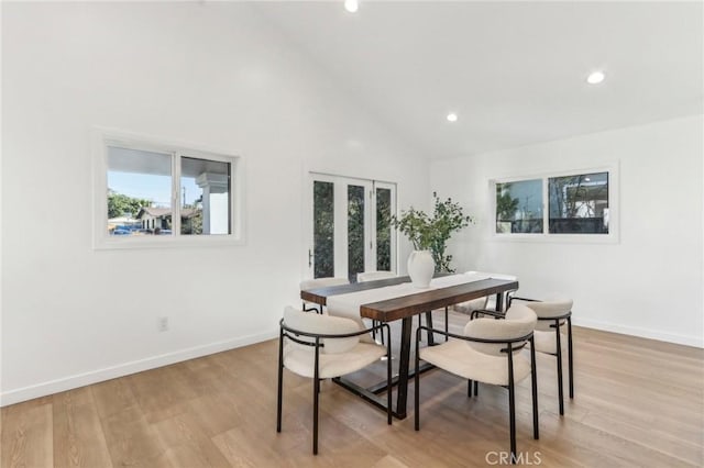 dining space featuring high vaulted ceiling and light hardwood / wood-style flooring