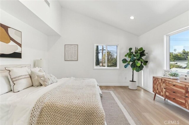 bedroom featuring high vaulted ceiling, light hardwood / wood-style floors, and multiple windows