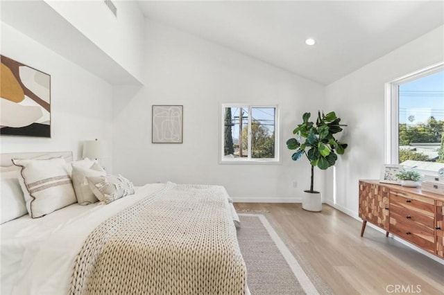 bedroom featuring multiple windows, vaulted ceiling, and light wood-type flooring