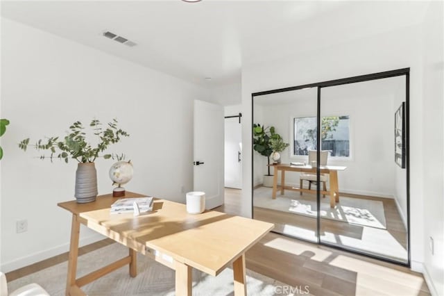 office with a barn door and light hardwood / wood-style flooring