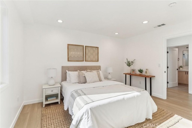 bedroom with light wood-type flooring and ensuite bath