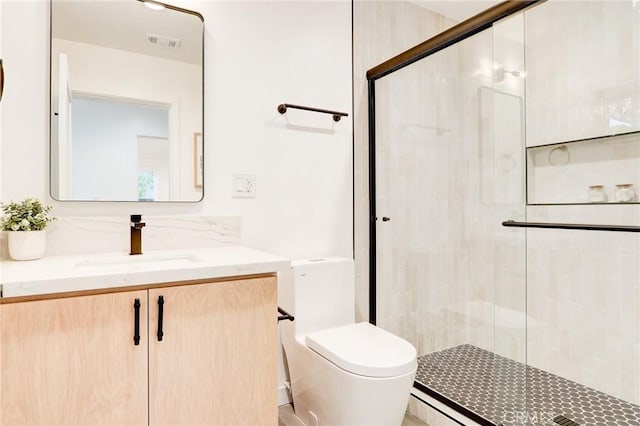 bathroom featuring vanity, a shower with shower door, and toilet