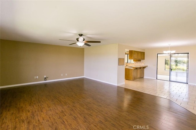 unfurnished living room featuring light hardwood / wood-style floors and ceiling fan with notable chandelier