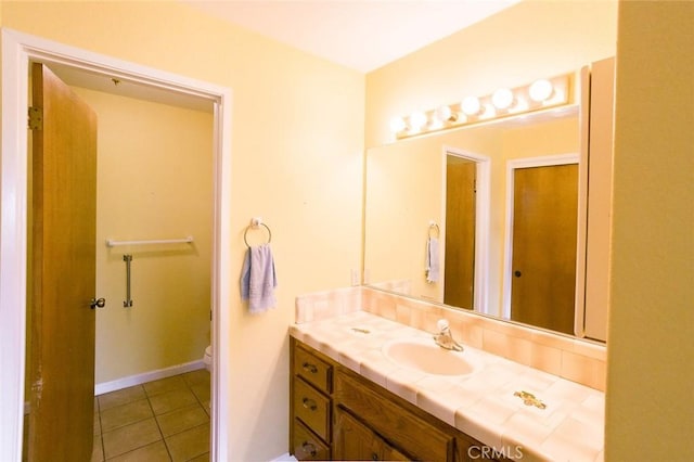 bathroom with toilet, vanity, and tile patterned flooring