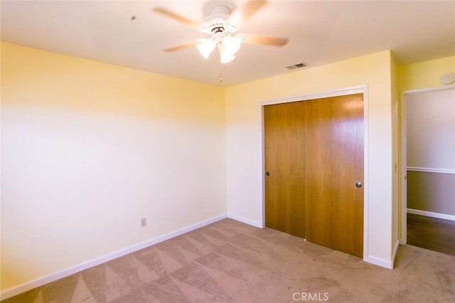 unfurnished bedroom featuring light carpet, a closet, and ceiling fan