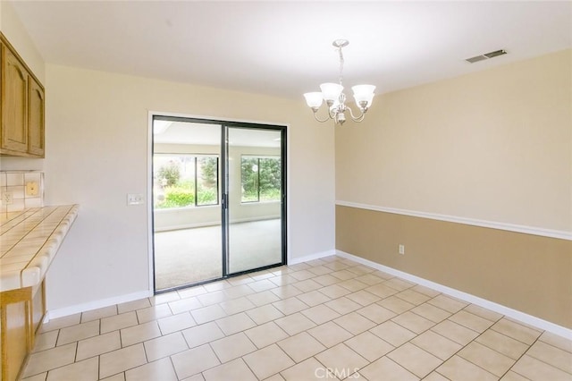 unfurnished dining area featuring light tile patterned flooring and a chandelier