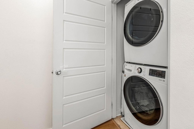 laundry area featuring stacked washer and clothes dryer and light wood-type flooring