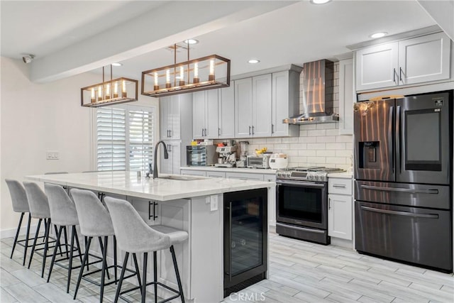 kitchen with wine cooler, appliances with stainless steel finishes, a kitchen breakfast bar, wall chimney exhaust hood, and tasteful backsplash