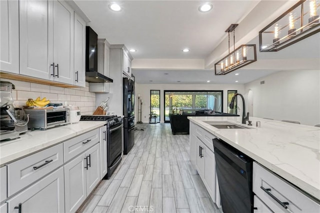 kitchen featuring white cabinetry, backsplash, wall chimney range hood, pendant lighting, and black appliances