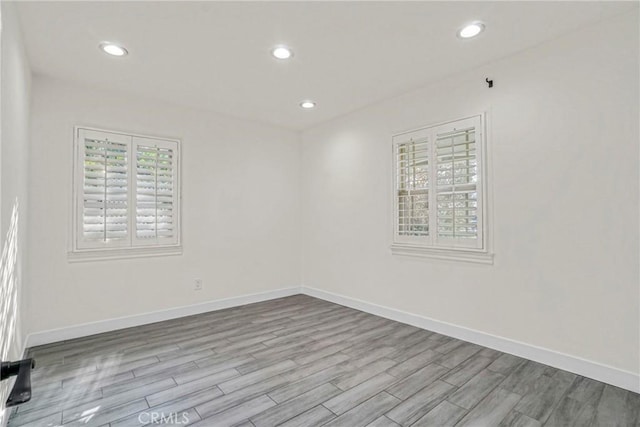 empty room with recessed lighting, baseboards, and wood finished floors