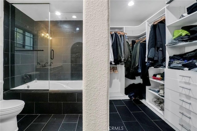 bathroom with tile patterned floors, toilet, and combined bath / shower with glass door