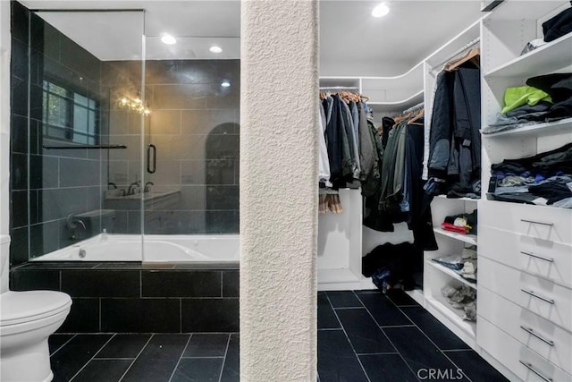 bathroom with tile patterned floors, a spacious closet, toilet, and tiled shower / bath combo