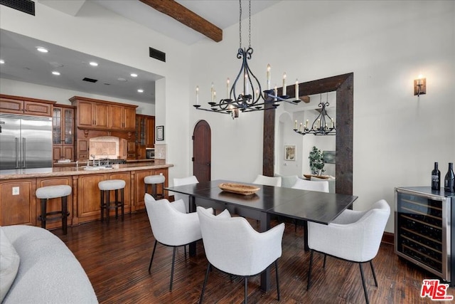 dining space featuring dark hardwood / wood-style floors, a notable chandelier, a towering ceiling, wine cooler, and beamed ceiling