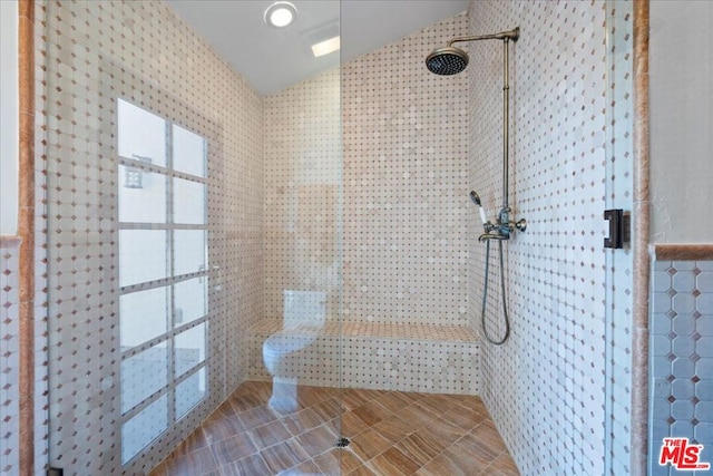 bathroom with tile walls, lofted ceiling, and a tile shower