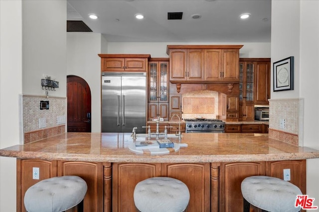 kitchen with backsplash, premium appliances, and kitchen peninsula