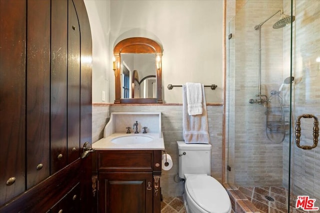 bathroom featuring a shower with shower door, tile walls, toilet, and vanity