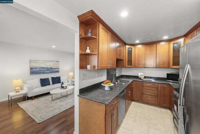 kitchen with sink, light tile patterned floors, dark stone counters, and appliances with stainless steel finishes