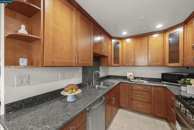 kitchen featuring sink, dark stone counters, appliances with stainless steel finishes, and light tile patterned flooring