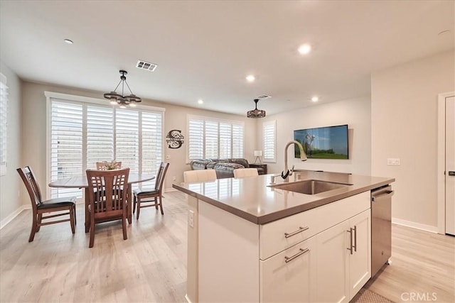 kitchen with sink, an island with sink, white cabinets, decorative light fixtures, and stainless steel dishwasher