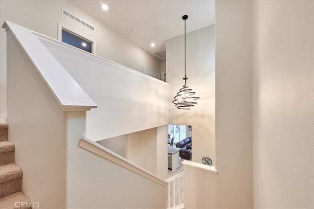 staircase with a notable chandelier