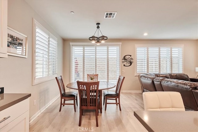 dining area featuring a notable chandelier, light hardwood / wood-style floors, and a healthy amount of sunlight