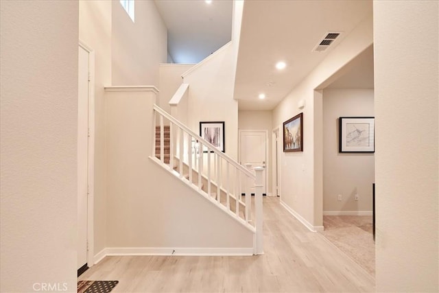 entrance foyer featuring a towering ceiling and light wood-type flooring