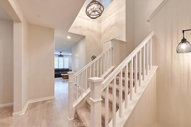 stairs with wood-type flooring and a chandelier