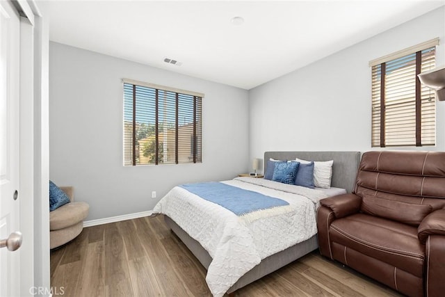 bedroom with multiple windows and hardwood / wood-style floors