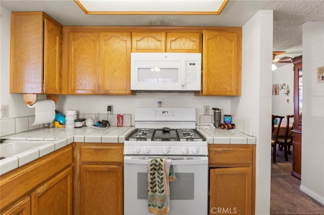 kitchen featuring tile counters, ceiling fan, carpet, and white appliances