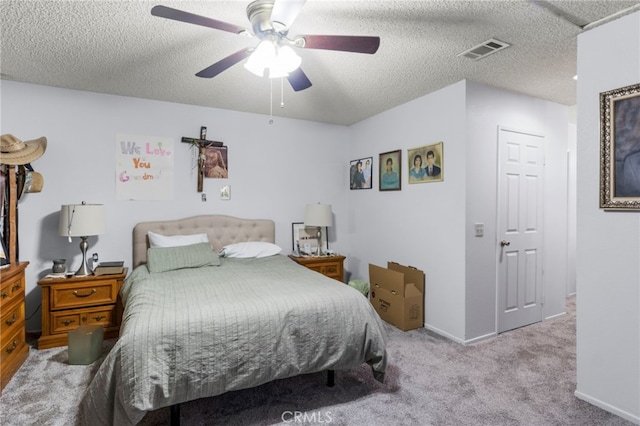 bedroom with ceiling fan, light colored carpet, and a textured ceiling