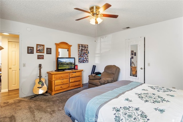 bedroom featuring ceiling fan, a textured ceiling, and dark colored carpet