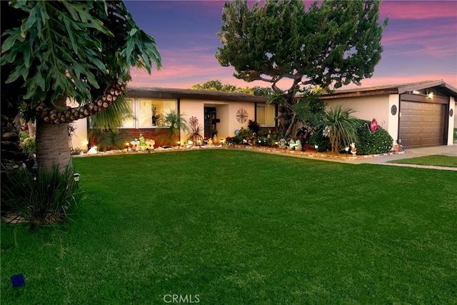 ranch-style house featuring a garage and a yard