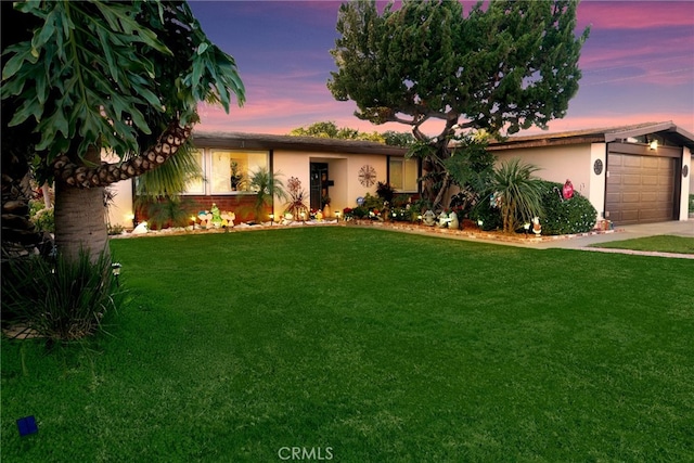 ranch-style home with a garage and a yard