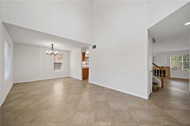 unfurnished living room featuring a high ceiling and a chandelier