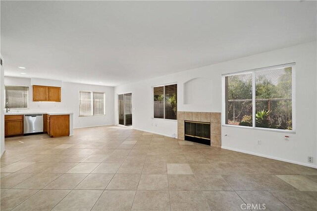 unfurnished living room featuring sink, a wealth of natural light, a fireplace, and light tile patterned floors