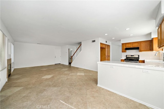 kitchen with tile countertops, sink, and stainless steel gas stove