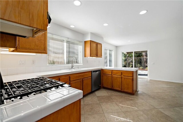 kitchen with sink, light tile patterned floors, stainless steel dishwasher, tile counters, and kitchen peninsula