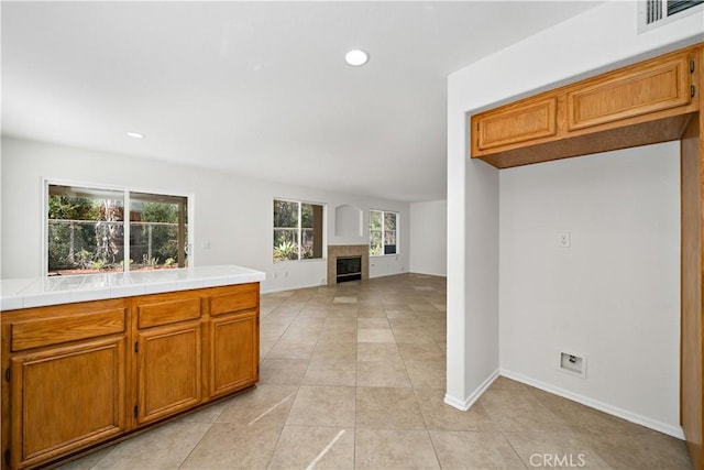 kitchen featuring light tile patterned floors, tile counters, and a tile fireplace