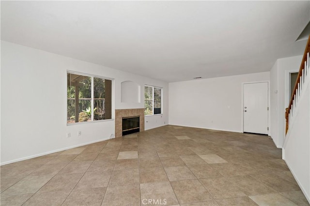 unfurnished living room featuring a tiled fireplace and light tile patterned floors