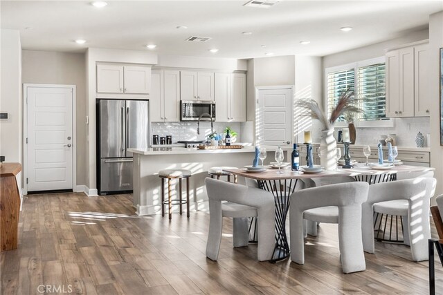 kitchen featuring a breakfast bar area, white cabinetry, a kitchen island, stainless steel appliances, and backsplash