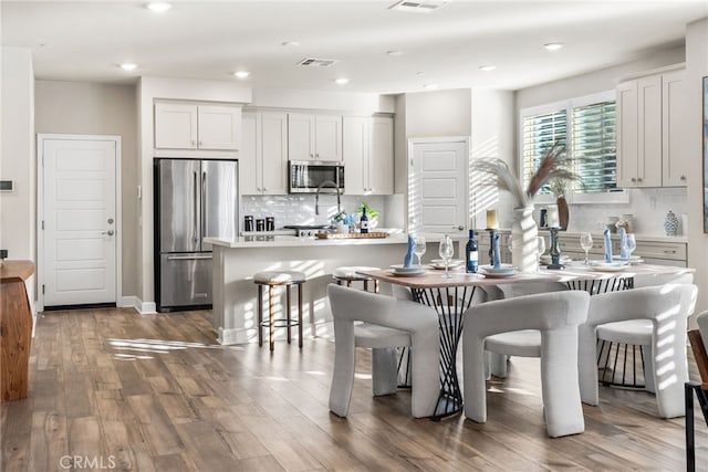 kitchen featuring a breakfast bar area, dark hardwood / wood-style floors, a kitchen island, stainless steel appliances, and white cabinets