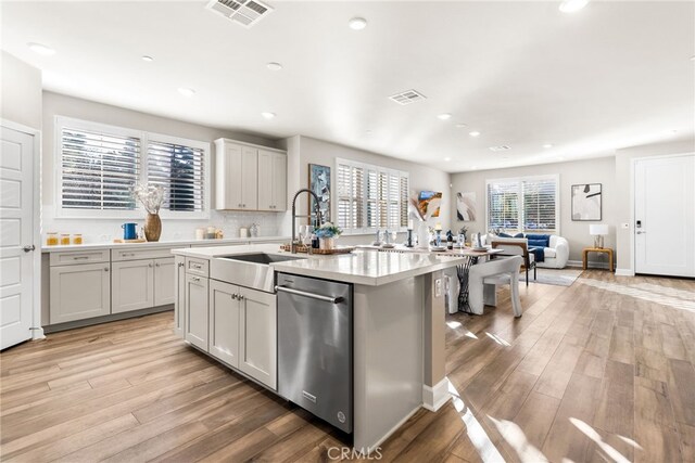 kitchen featuring a kitchen island with sink, sink, light hardwood / wood-style floors, and dishwasher